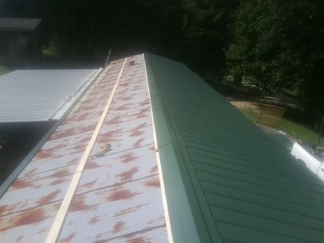 Old rusted panels beside newly installed green metal roofing — Wind Damage Roof Repair by Roofing Brothers in Long Branch