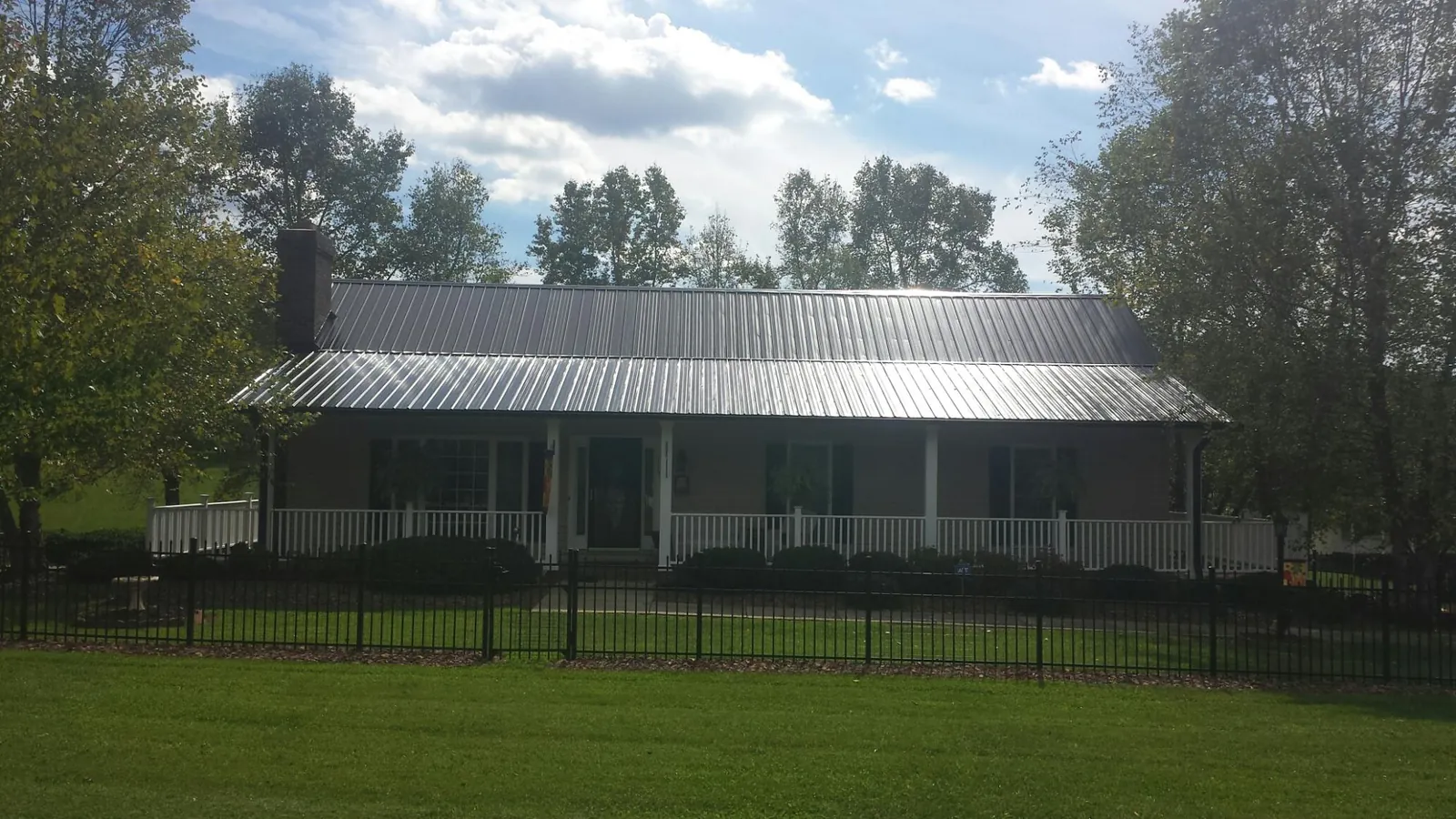 Gray metal roof on a brick ranch with a full width front porch — Gutter Guard Installation work by our crew in Long Branch