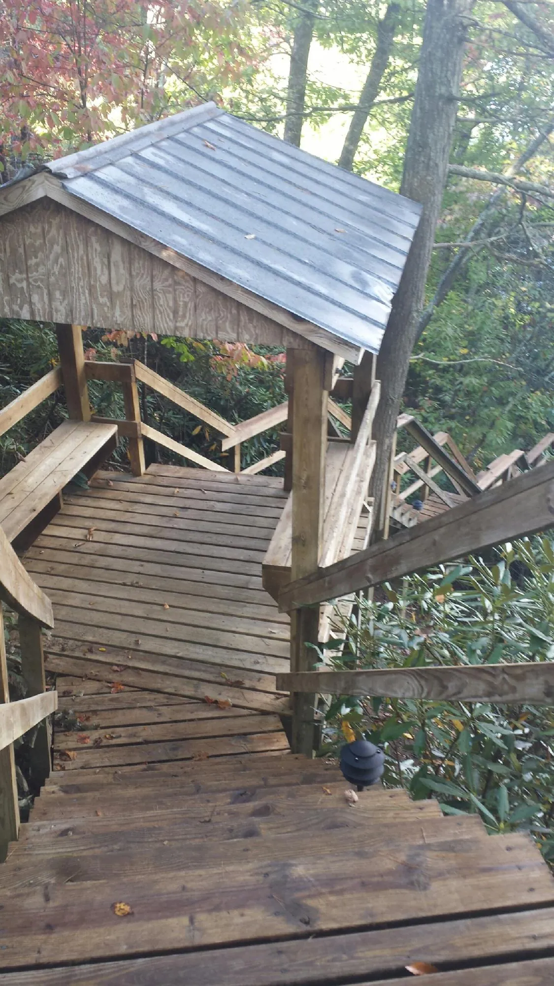 Metal roofed shelter over wooden steps on a wooded walkway — Skylight Repair & Installation work by our crew in Long Branch