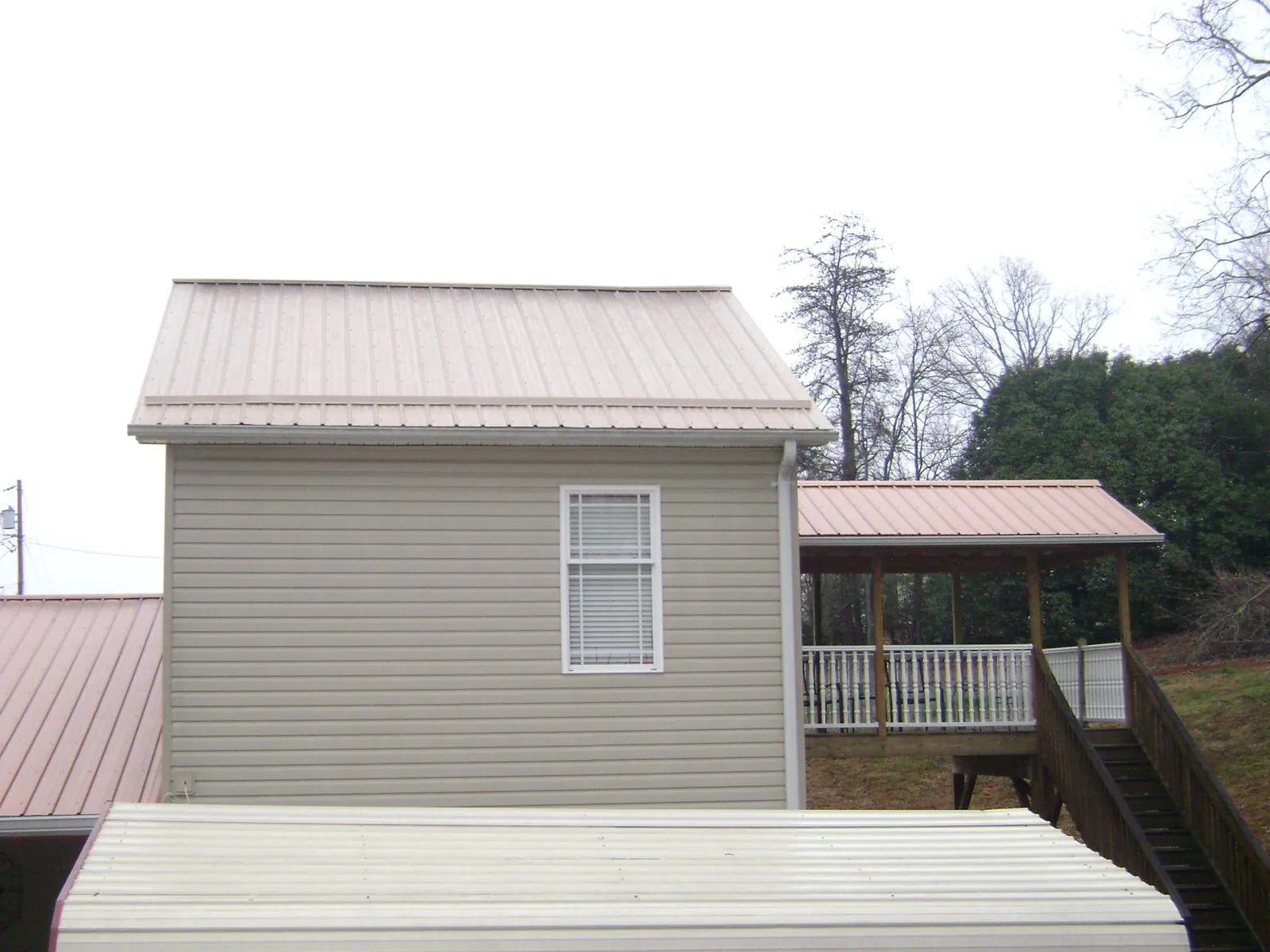 Tan metal roofs on a two story addition and attached porch, from a Roof Replacement job in Long Branch