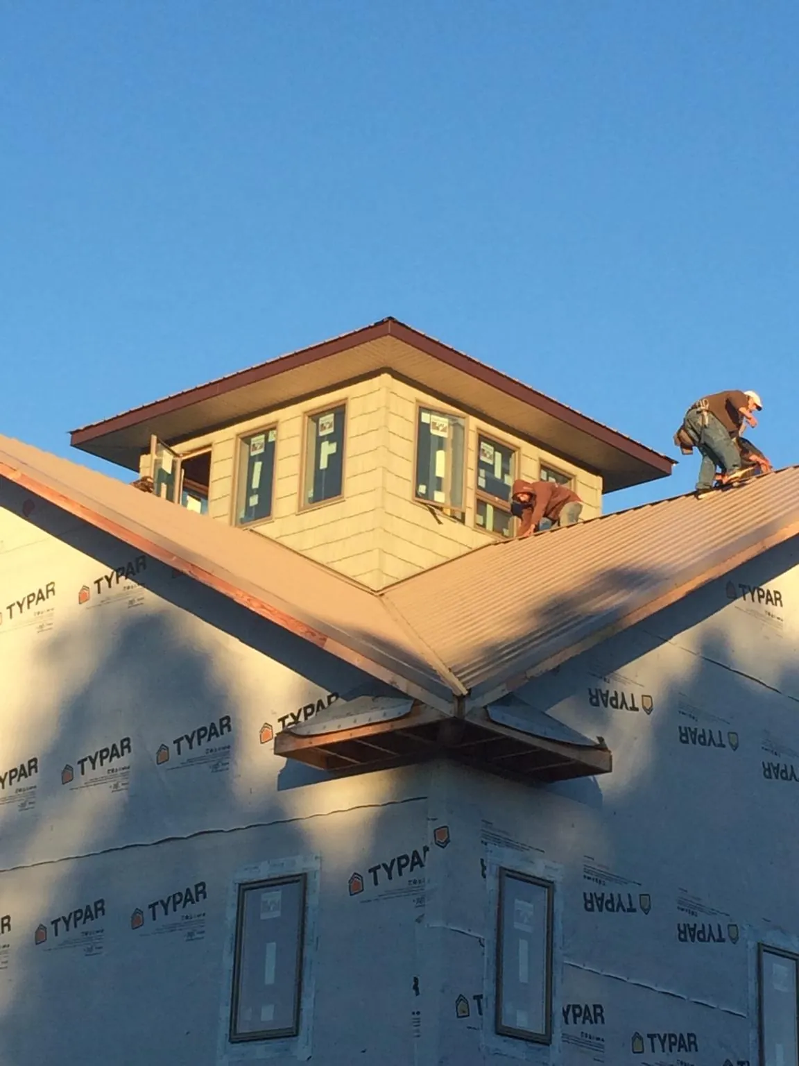 Roofers working around a rooftop cupola on a new metal roof at sunset — Roof Waterproofing in Long Branch by Roofing Brothers